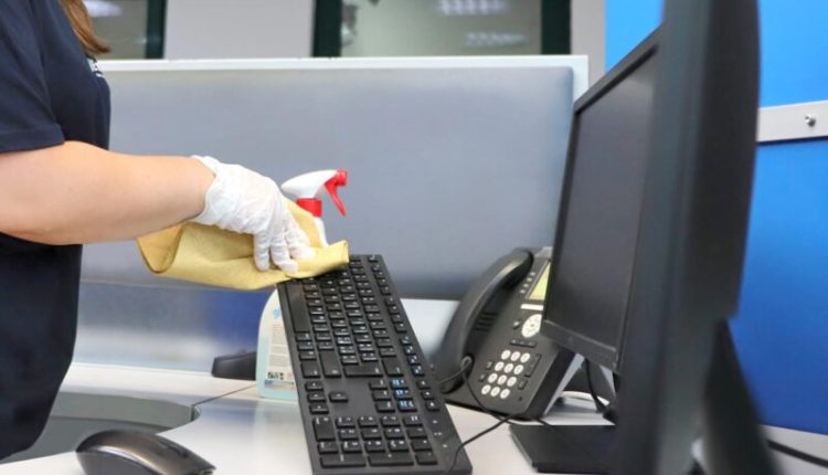 donna addetta alle pulizie che igienizza cornetta telefono in ufficio